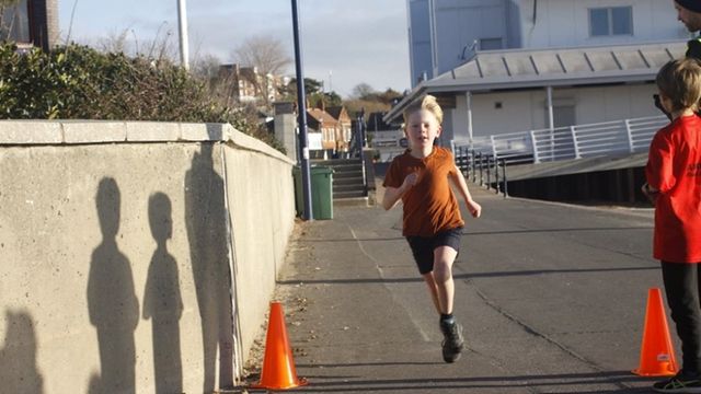 A young boy runs by the coast on a sunny day